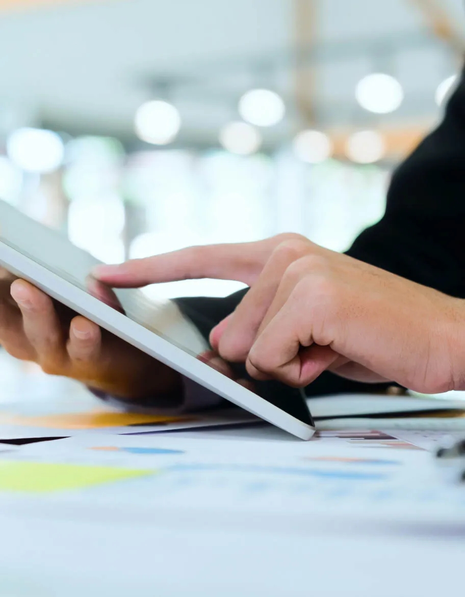 ISO/IEC 27018 advisor sitting at the desk and working with a tablet.