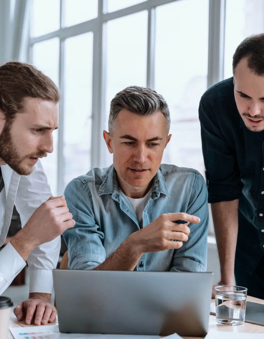 Three ISO consultants looking at the laptop's screen, discussing the latest ISO/IEC 27017 changes