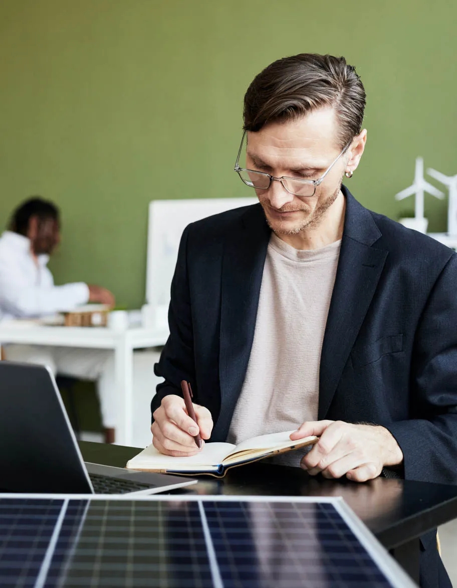 ISO 14001 advisor participating in a meeting and taking notes.