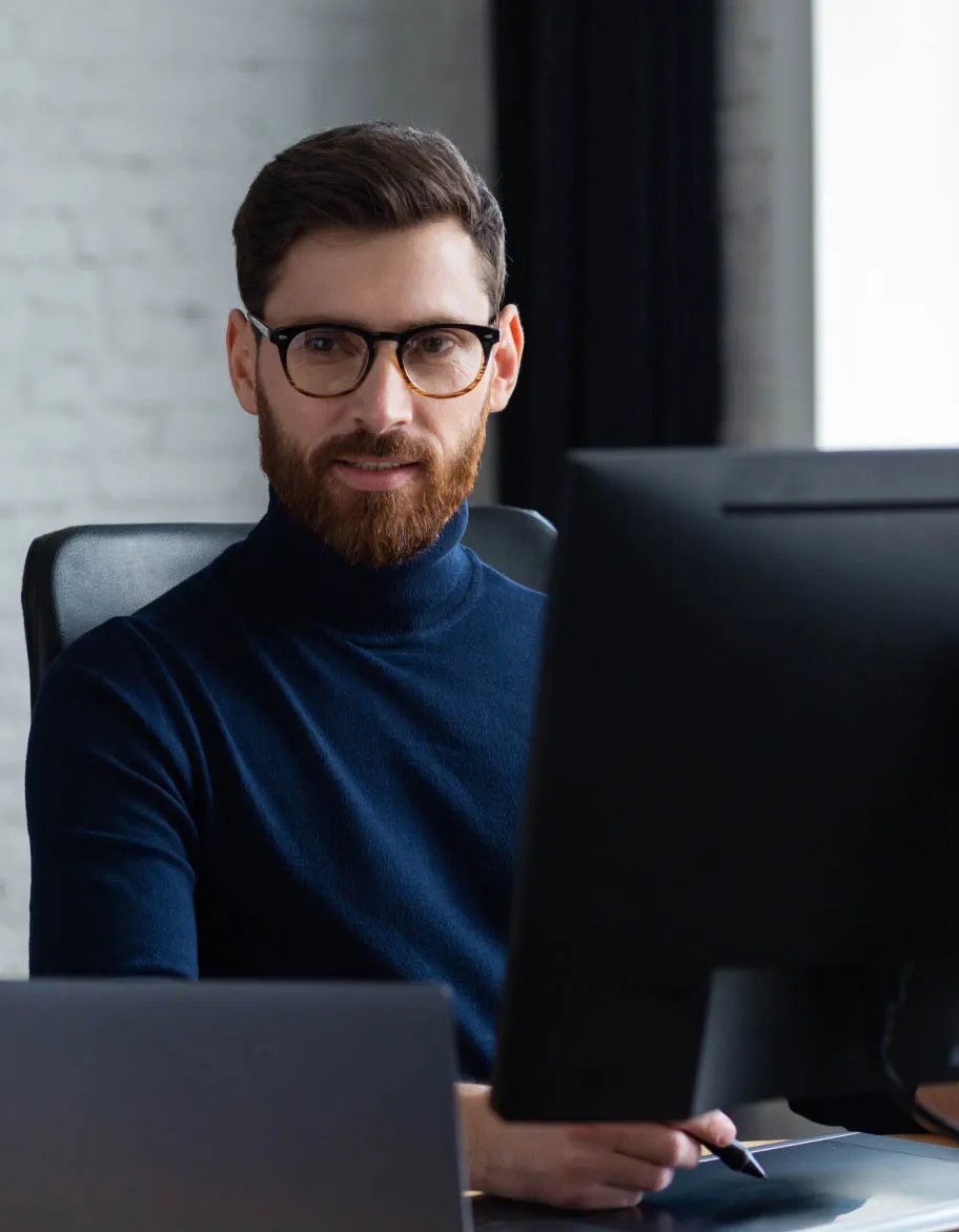 ISO 27701 advisory expert in blue sweater working in the office at his desk.