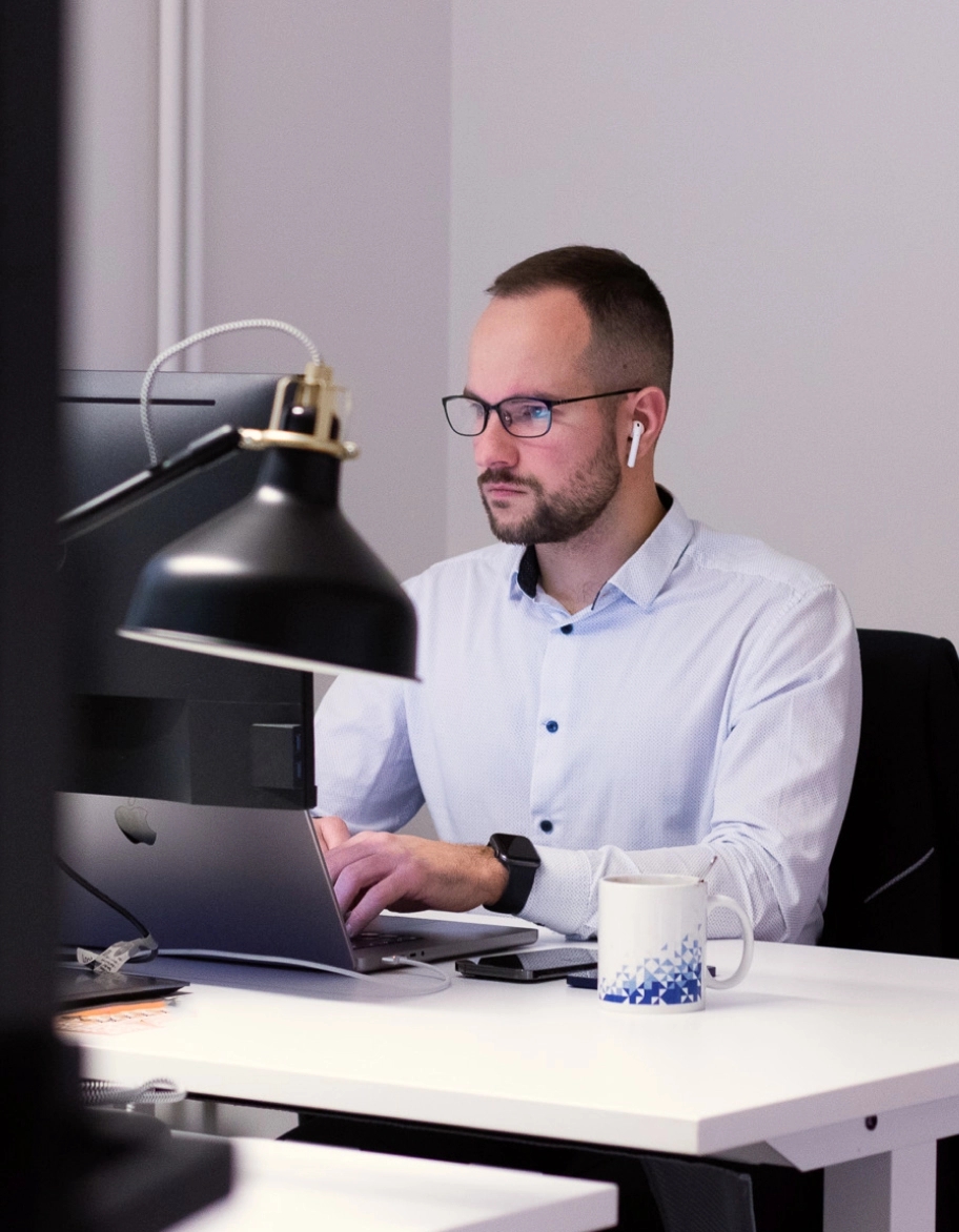 Consultant ISO assis à son bureau et travaillant sur un ordinateur portable.