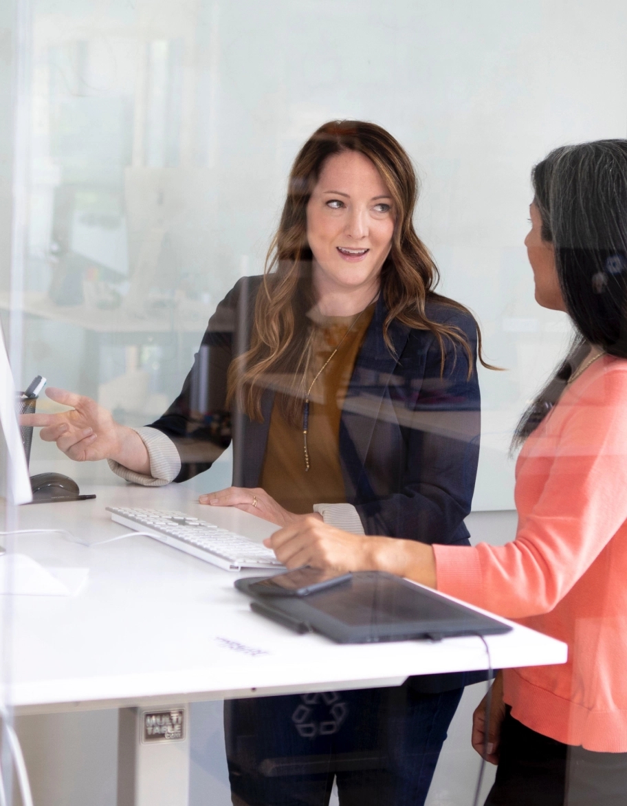 Two ISO consultants standing at the desk and having a discussion while pointing at the monitor