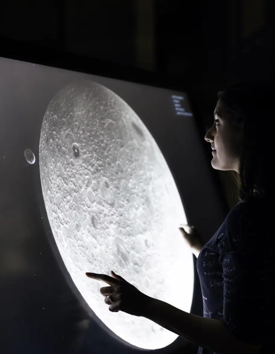 A person virtually exploring the moon's surface with the help of a large screen.